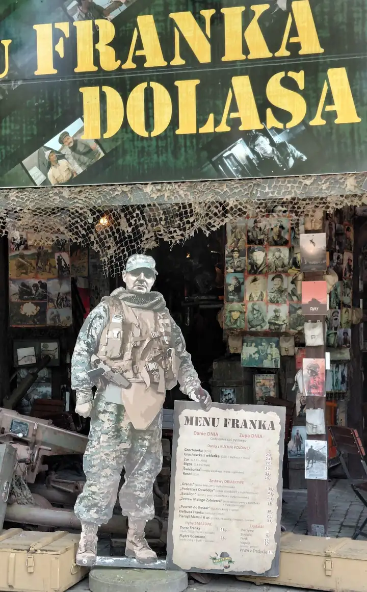 Wejście do U Franka Dolasa: żołnierz w mundurze pod zielonym szyldem z napisem U Franka Dolasa