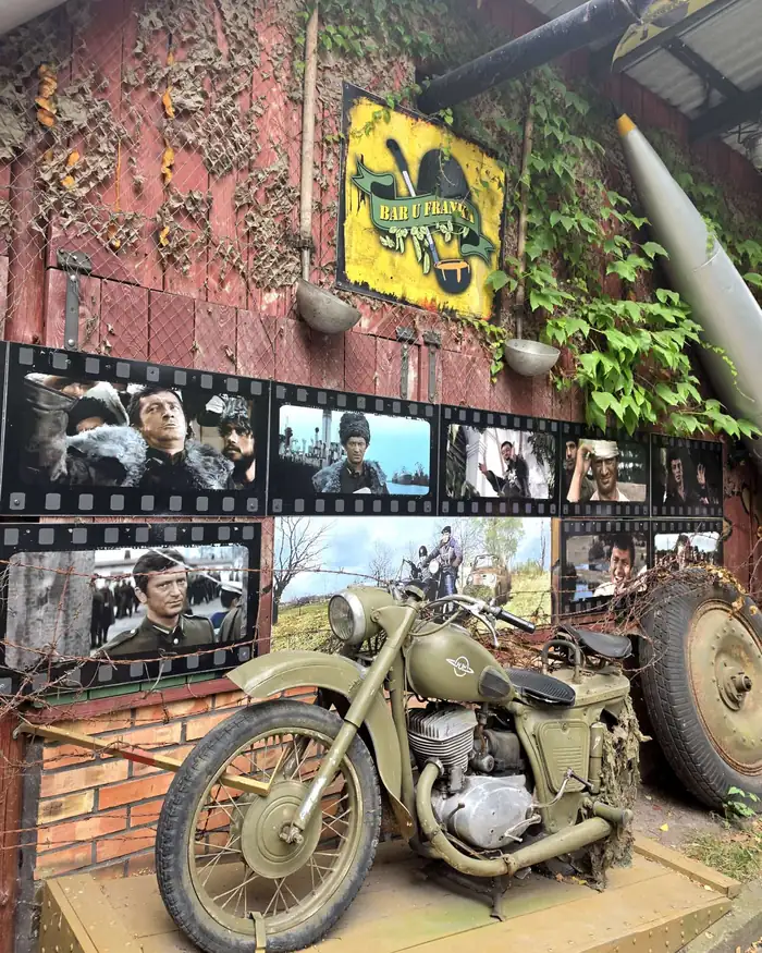 Wojskowy motocykl na tle ściany ze zdjęciami
